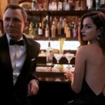 Daniel Craig, in a tuxedo, and Ana de Armas, in a black dress, stand at a bar in "No Time to Die."