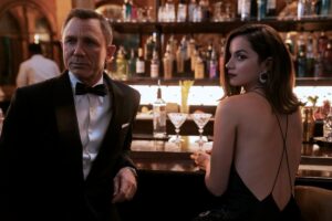 Daniel Craig, in a tuxedo, and Ana de Armas, in a black dress, stand at a bar in "No Time to Die."