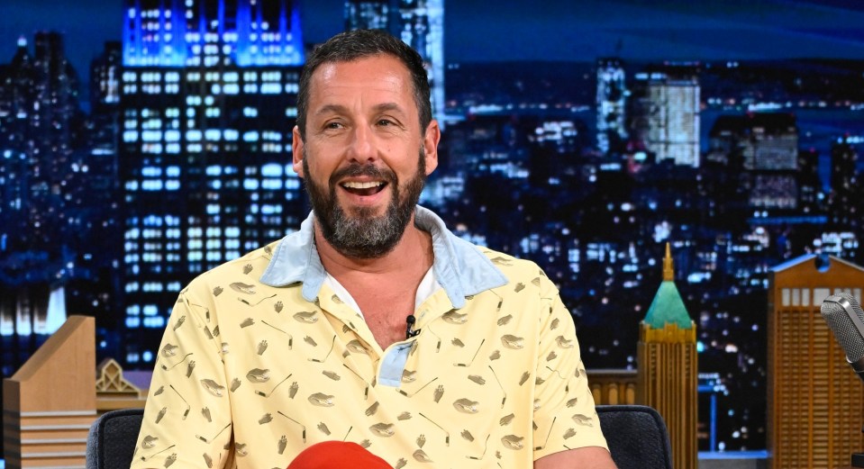 Adam Sandler smiling during an interview on The Tonight Show Starring Jimmy Fallon.