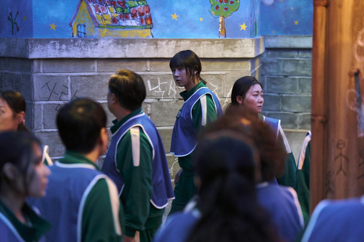 A woman in a blue vest in focus surrounded by others in blue vests seen from behind.