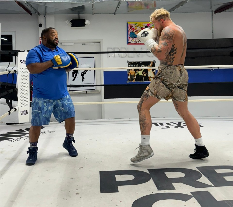 Boxer training in a boxing ring with a trainer.