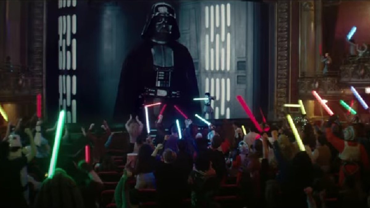 Darth Vader looms on screen as Star Wars fans raise their lightsabers in Coke ad.