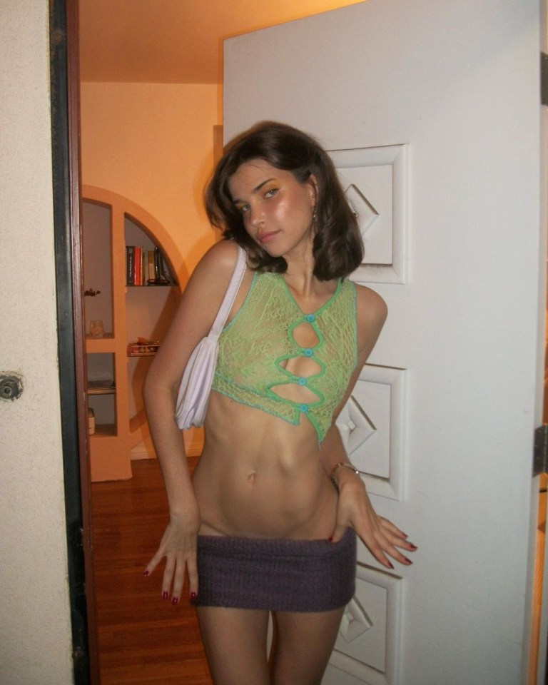 Woman in a green top and purple skirt standing in a doorway.