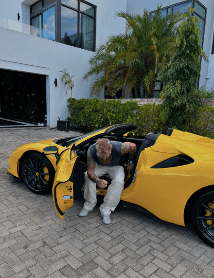 Man getting into a yellow convertible sports car.