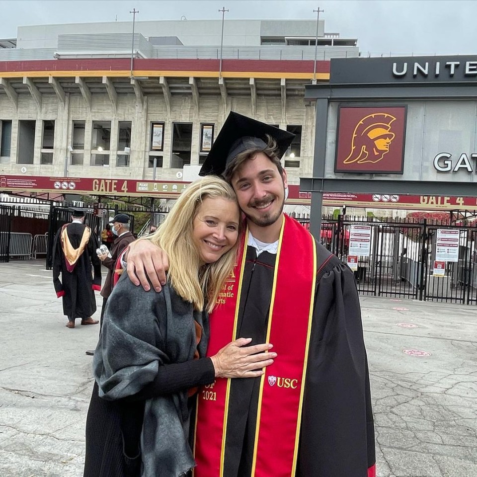 A woman and a young man in a USC graduation gown embrace in front of a stadium.