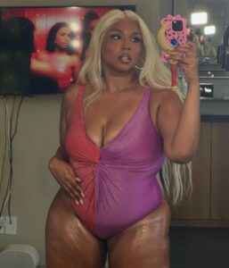 Lizzo in a two-toned swimsuit taking a selfie.
