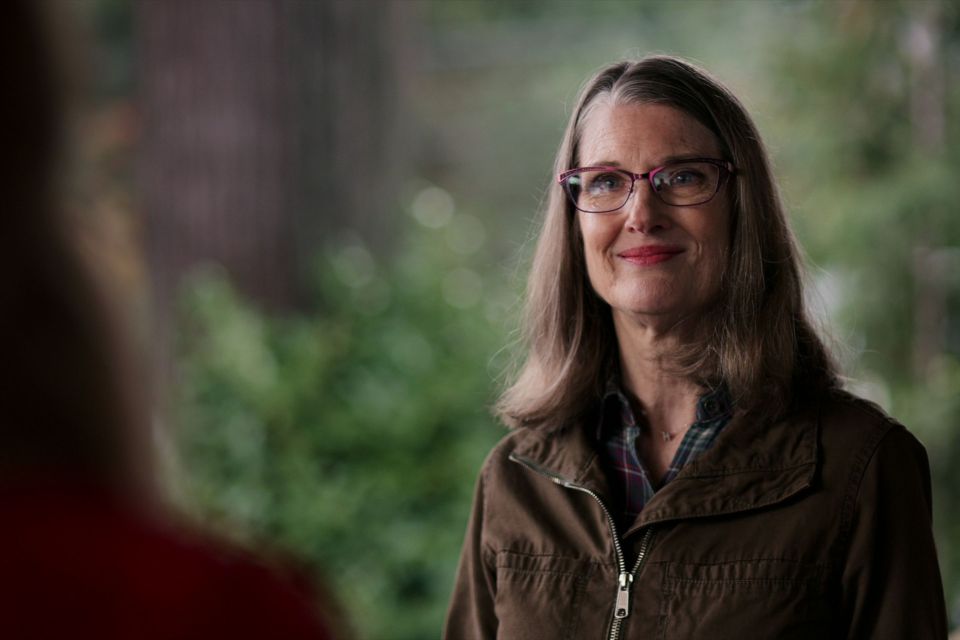 Woman wearing glasses and a brown jacket.