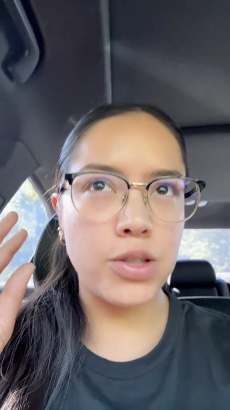 Woman in glasses talking in a car.
