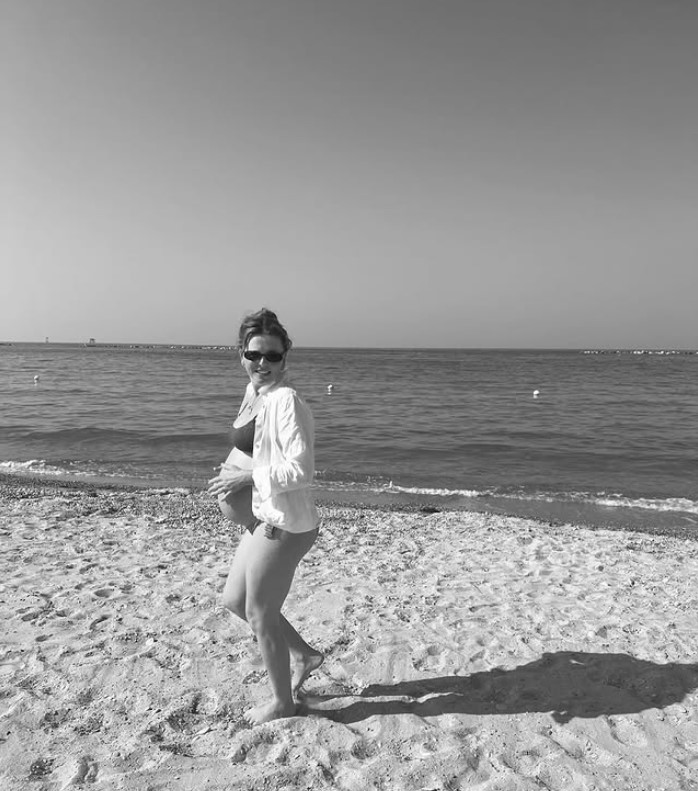 Black and white photo of a pregnant woman on a beach.