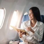 A smiling woman looks out of the window of an airplane