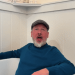 Man in teal sweater sitting in a bathtub.