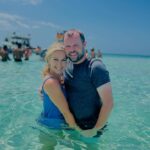 Couple embracing in shallow turquoise water.