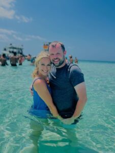 Couple embracing in shallow turquoise water.