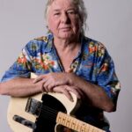 Portrait of Mick Ralphs, British guitarist, holding a guitar.