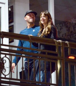 Dakota Johnson and Chris Martin on a balcony.