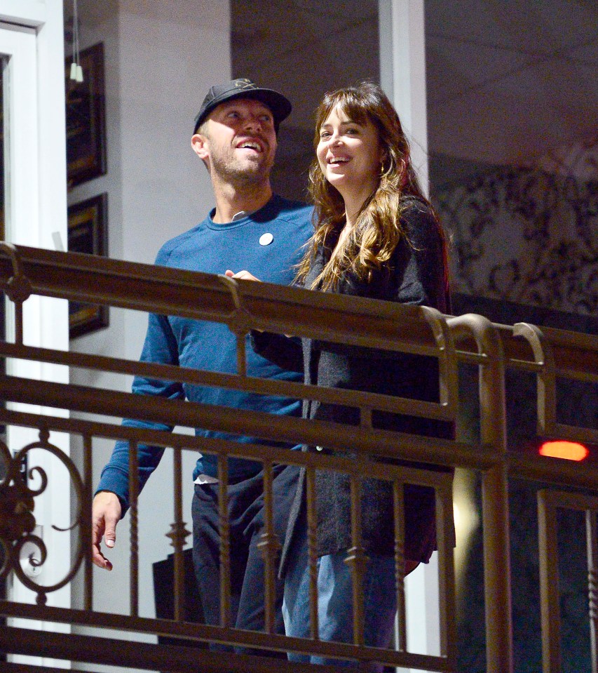 Dakota Johnson and Chris Martin on a balcony.