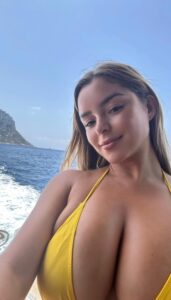 Demi Rose takes a selfie while wearing a yellow bikini top.