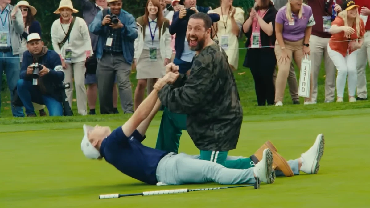 Adam Sandler holding a golfer by his arms on the ground and laughing in Happy Gilmore 2