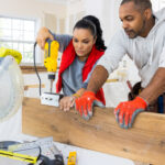 A couple working together to install floating shelves in a kitchen.