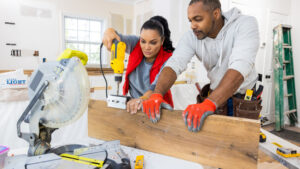A couple working together to install floating shelves in a kitchen.
