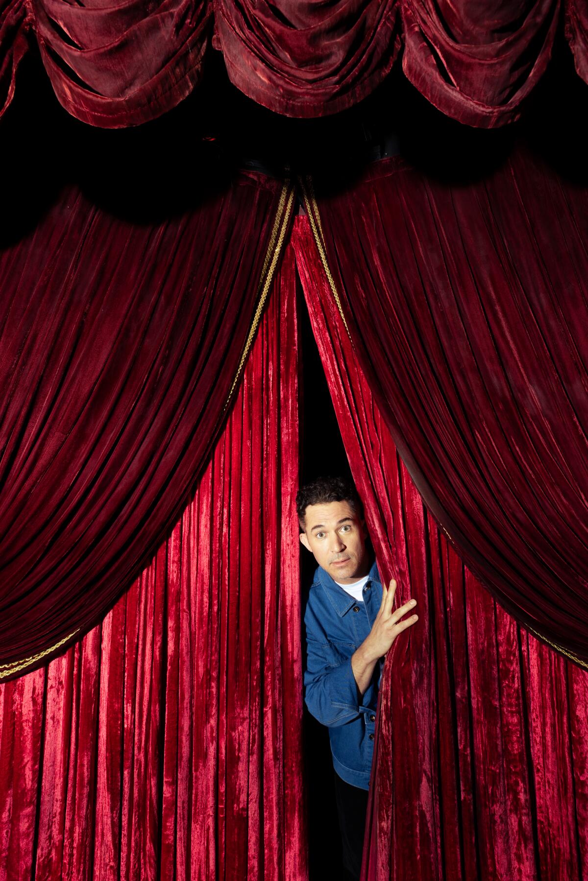 Man peaking from behind a red curtain