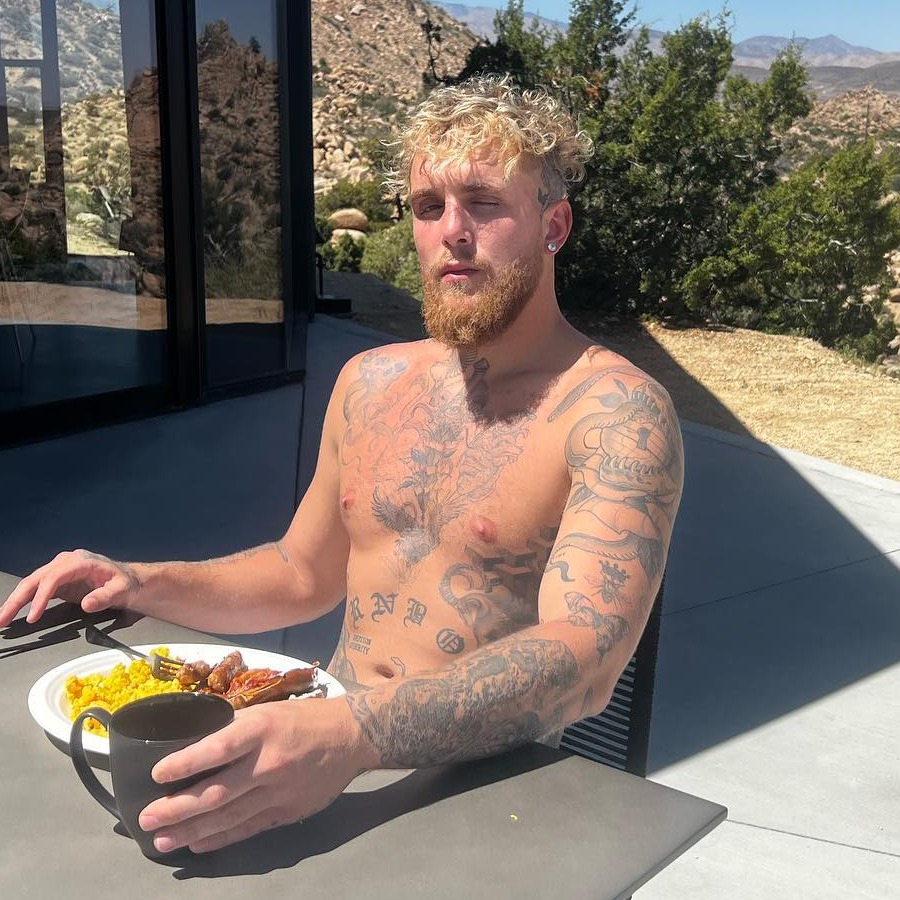 Man with tattoos eating breakfast outdoors.