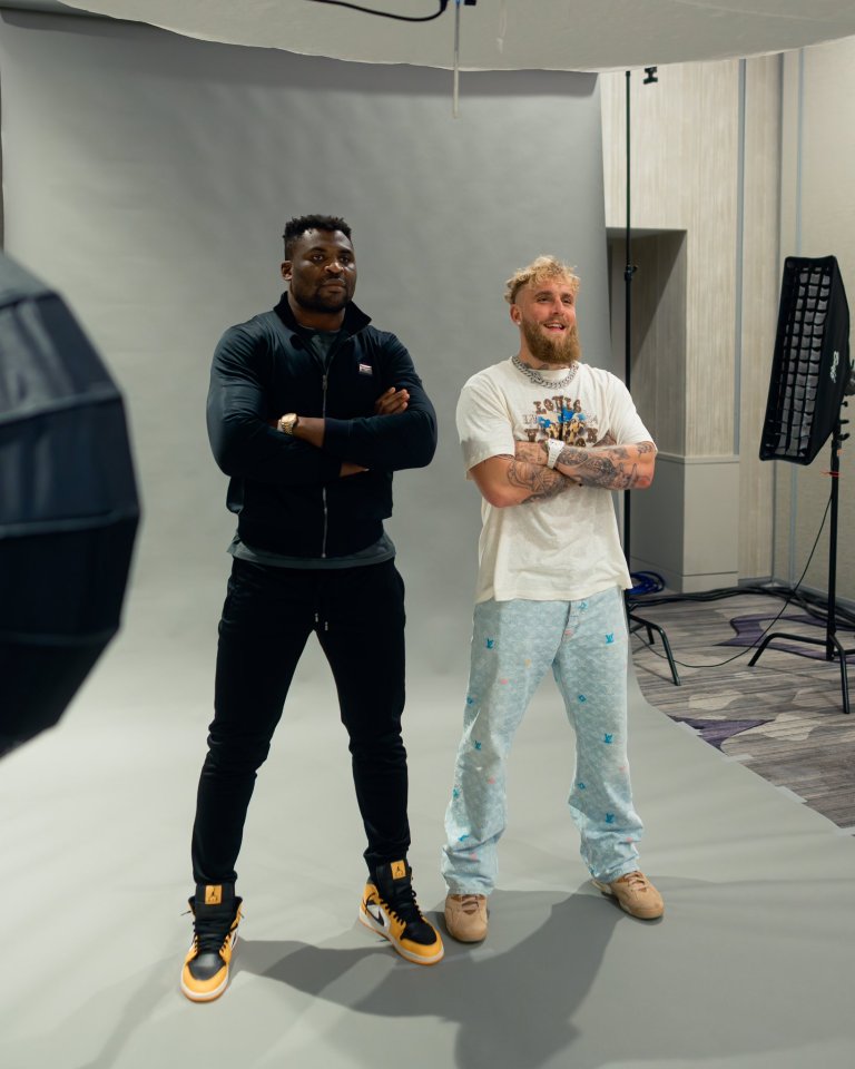 Two men standing in a photo studio, arms crossed.