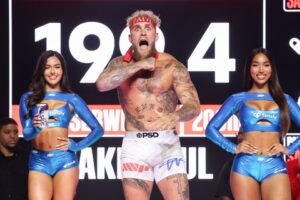 Jake Paul at a weigh-in, flanked by two women.