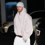 Justin Bieber wearing a light-colored hoodie, knit hat, and white pants in New York City.