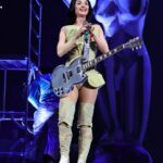 Katy Perry performing onstage with a guitar.