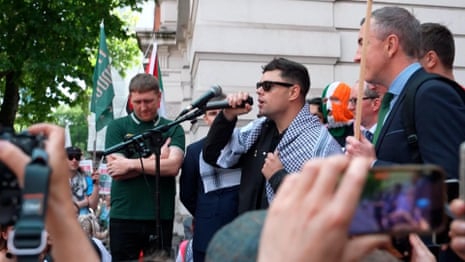 Crowds greet Kneecap rapper facing terrorism charge outside court – video