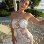 Kylie Jenner on a beach wearing a white lace dress.