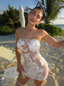 Kylie Jenner on a beach wearing a white lace dress.