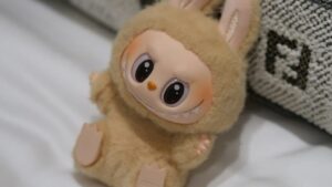 A Labubu figure sitting on a pillow.
