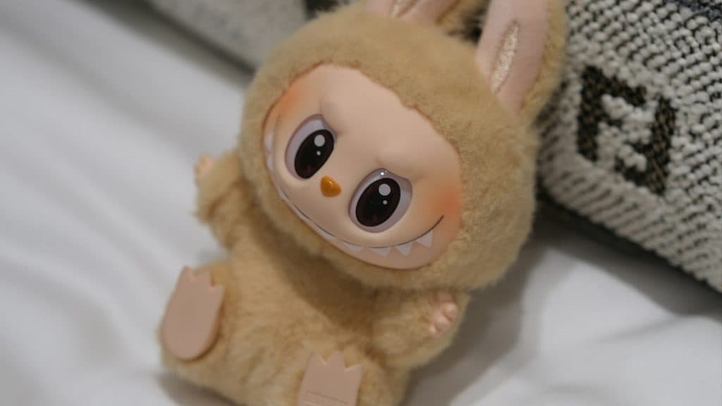 A Labubu figure sitting on a pillow.