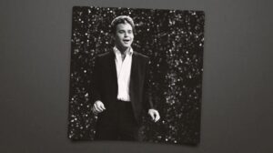 Black and white photo of a man in a suit singing.