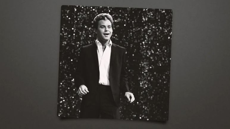 Black and white photo of a man in a suit singing.