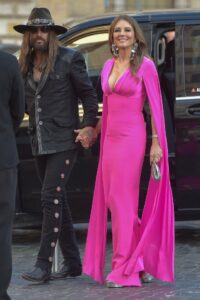 Liz Hurley and Billy Ray Cyrus holding hands at an event.