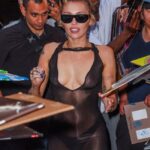Miley Cyrus signing autographs in a sheer black dress.