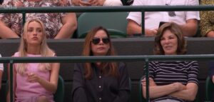 Three women seated in stadium seats.