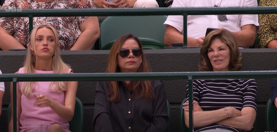 Three women seated in stadium seats.