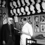 An injured man with a bandage around his face speaks to a doctor