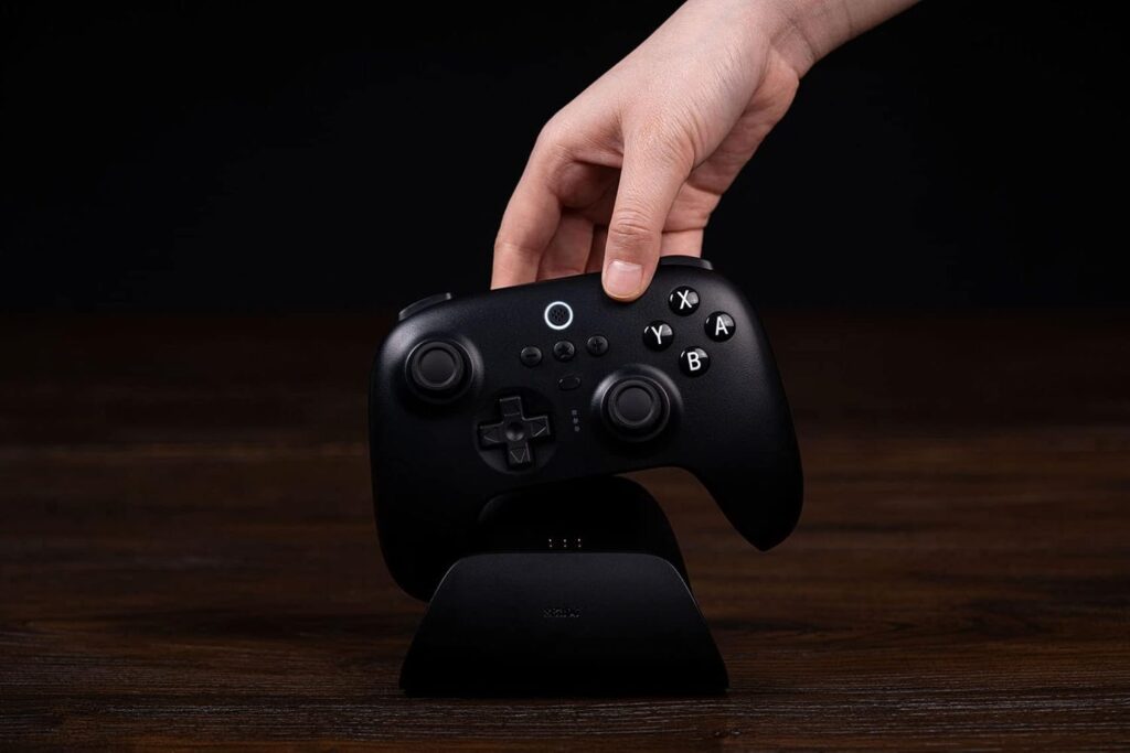 A hand putting an 8BitDo controller into its charging doc.