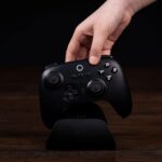 A hand putting an 8BitDo controller into its charging doc.