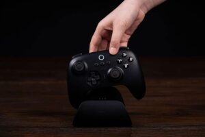 A hand putting an 8BitDo controller into its charging doc.