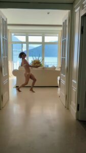 Halle Berry in a bikini carrying flowers in a luxurious room.