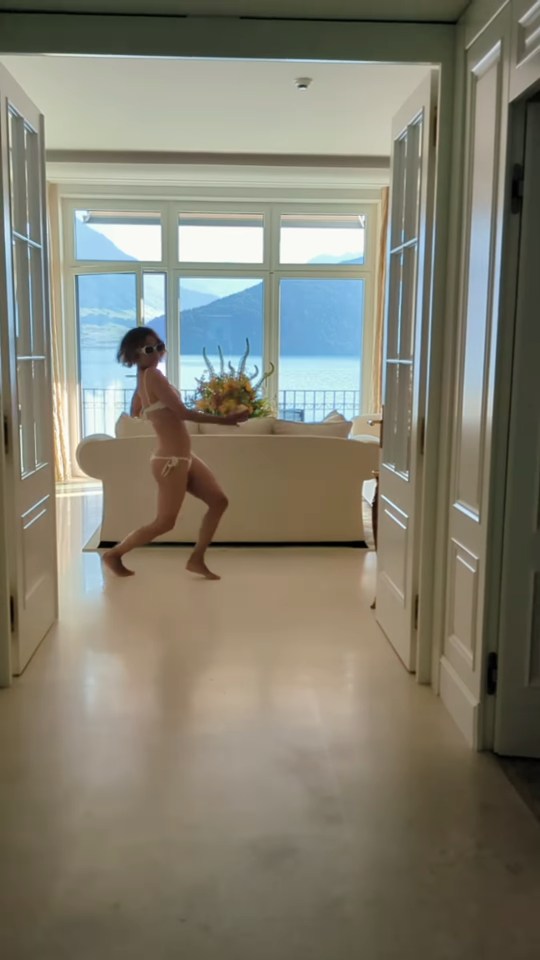 Halle Berry in a bikini carrying flowers in a luxurious room.
