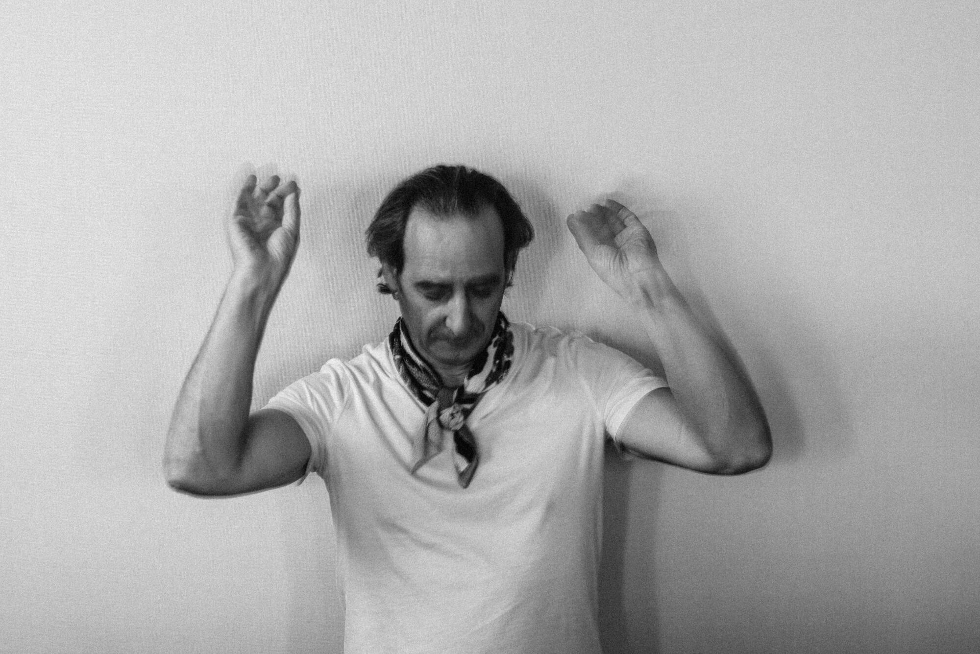 A conductor raises his arms, lost in a passage of music.
