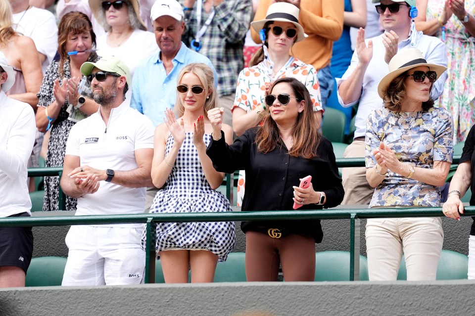 Taylor Fritz's partner applauds after his Wimbledon match.