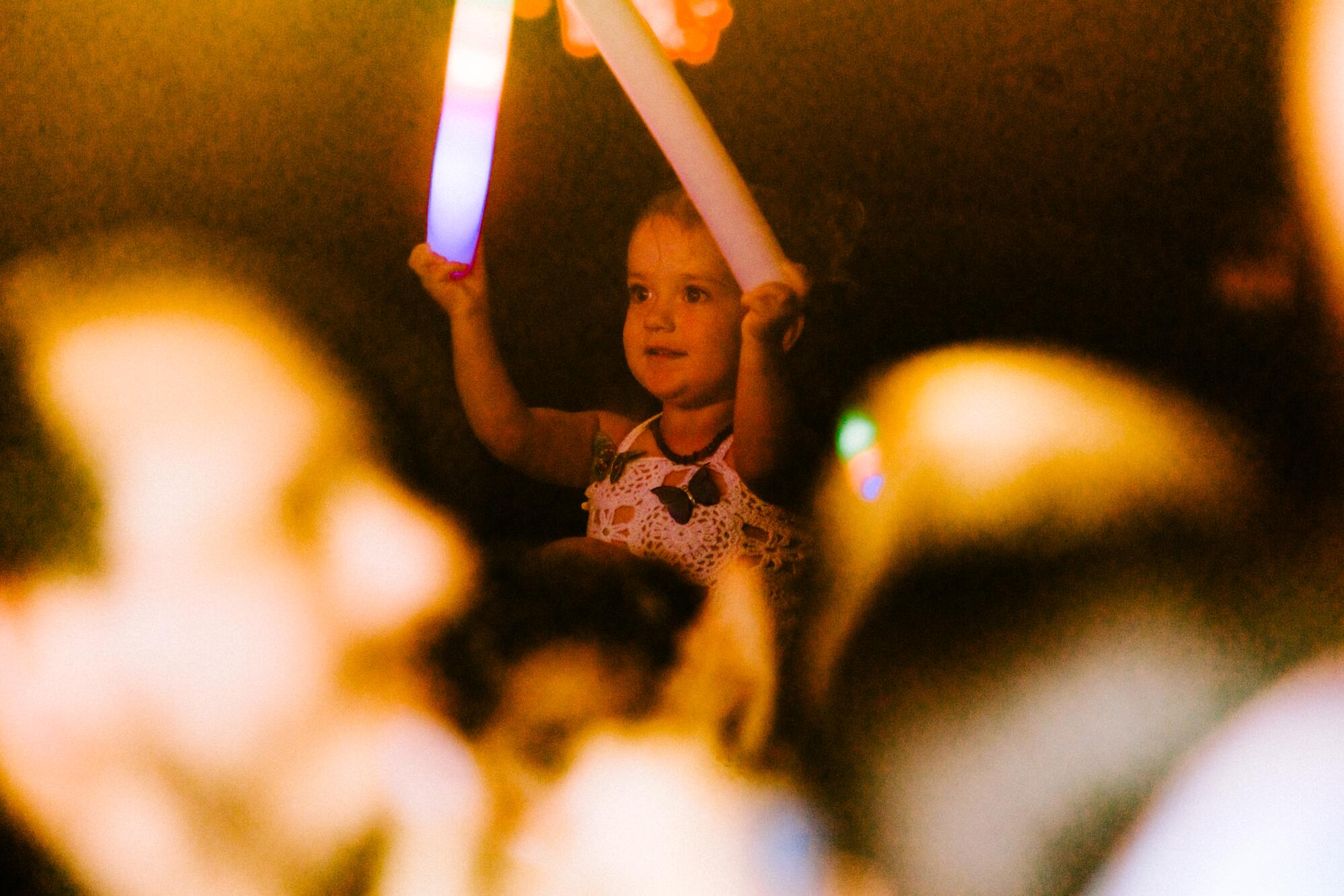 A baby holding two glow sticks.